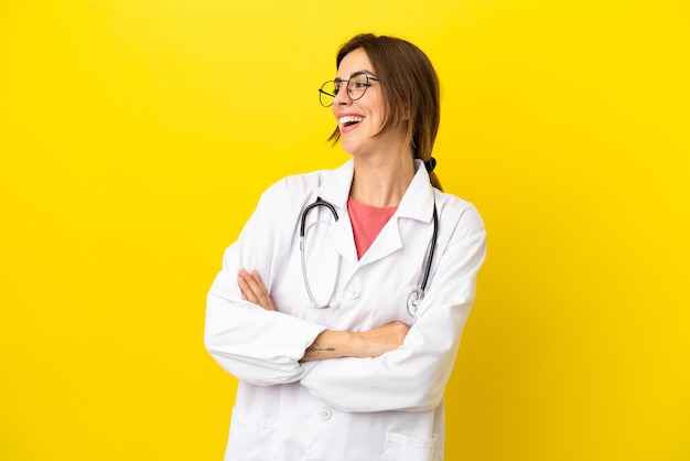 Kobieta lekarz odizolowana na żółtym tle szczęśliwa i uśmiechnięta