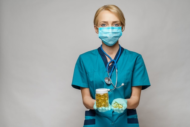 Kobieta lekarz pielęgniarka noszenie maski ochronne i rękawice gumowe lub lateksowe - trzymając puszkę pigułek
