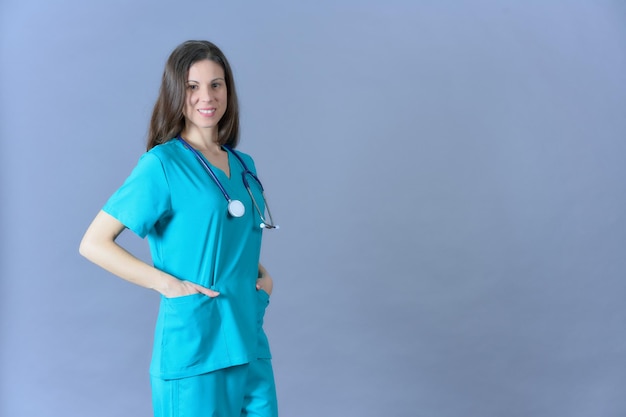 Kobieta lekarz pozuje ze stetoskopem na niebieskim tle w mundurze medycznym