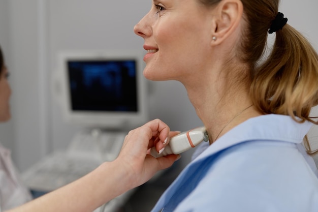 Zdjęcie kobieta lekarz przeprowadzająca ultradźwięki tarczycy i węzłów chłonnych w bliskiej odległości kompletne badanie medyczne w nowoczesnej klinice