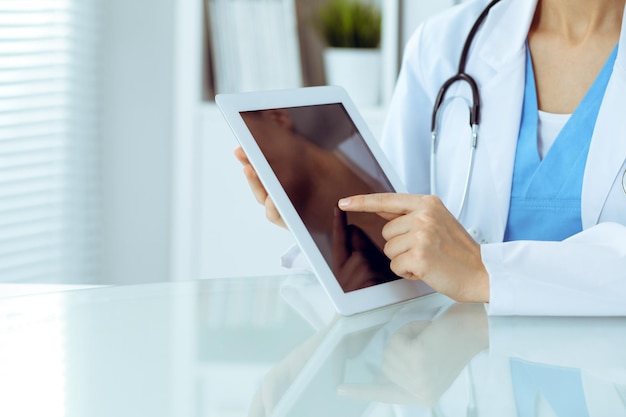 Kobieta lekarz przy użyciu komputera typu tablet siedząc w miejscu pracy zbliżenie rąk Medycyna opieki zdrowotnej i pomocy koncepcji