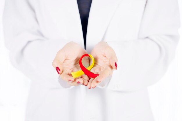 Kobieta lekarz ręce trzymając czerwoną i żółtą wstążkę