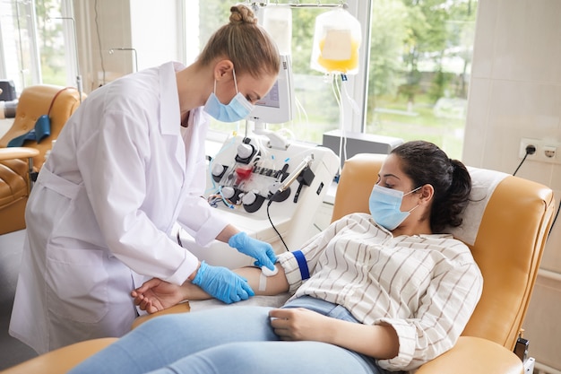 Kobieta lekarz w białym fartuchu trzymając badanie lekarskie w laboratorium, ona pobiera próbki krwi od pacjenta