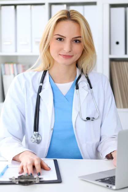 Kobieta lekarz wypełniania formularza medycznego siedząc przy biurku. Koncepcja medycyny i opieki zdrowotnej.