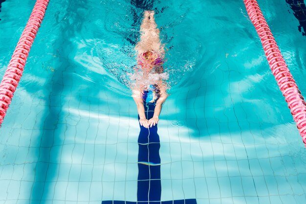 Kobieta lekkoatletycznego pływanie z kapeluszem do pływania i okularami w basenie