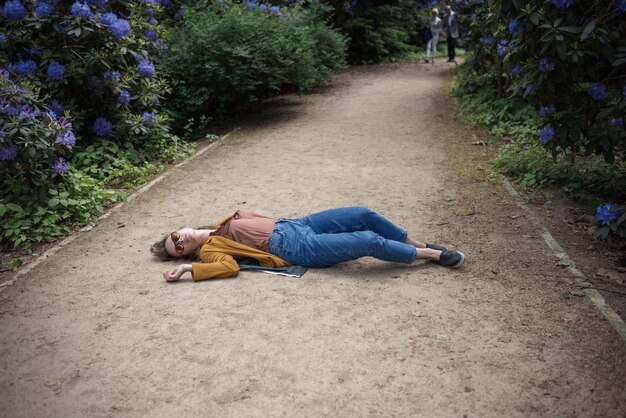 Zdjęcie kobieta leżąca na chodniku pośród roślin