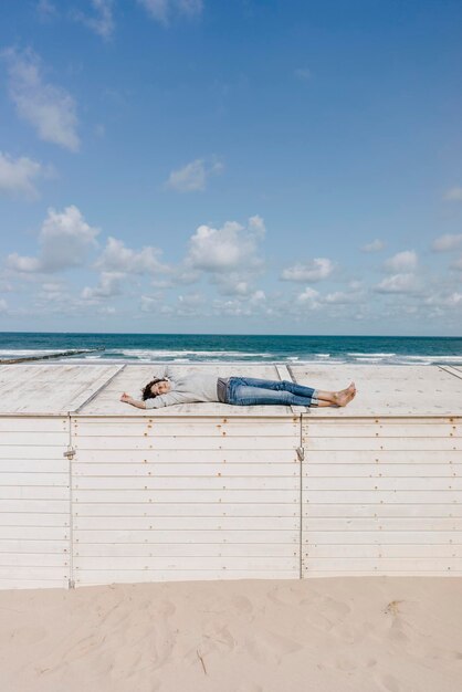 Kobieta leżąca na drewnianym pudełku na plaży