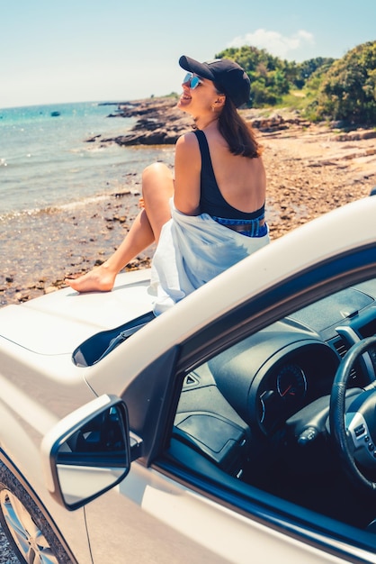 Kobieta leżąca na masce samochodu z widokiem na morze lato plaża