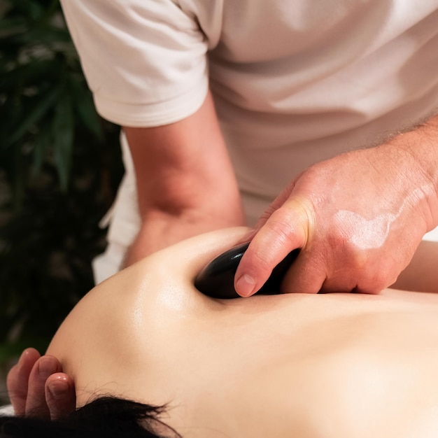 Kobieta leżąca podczas masażu gorącymi kamieniami na plecach w azjatyckim spa i centrum odnowy biologicznej