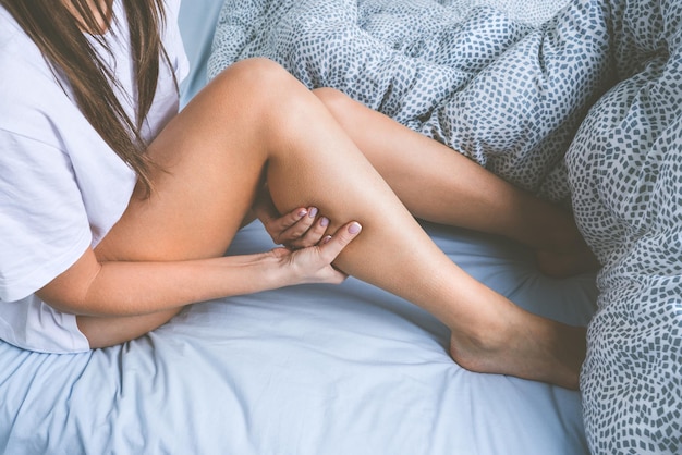 Kobieta leżąca w łóżku cierpiąca na skurcze mięśni nóg Ból mięśni lub ból nóg podczas snu