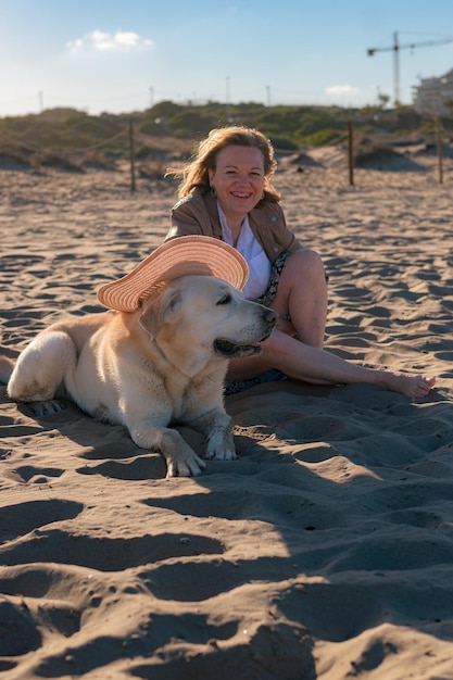 Kobieta lubi zakładać kapelusz na swojego psa na plaży