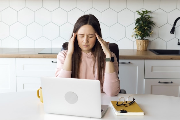 Kobieta ma ból głowy od pracy przy komputerze