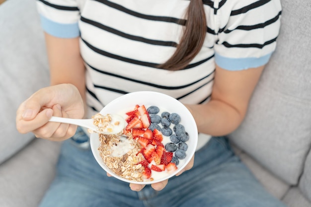 Kobieta ma pyszne zdrowe śniadanie w domu rano Opieka zdrowotna kobieta zjada jogurt z granolą i owocami jagodowymi Zdrowa żywność Witaminy czysta dieta dieta detox wegetariańska żywność ekologiczna