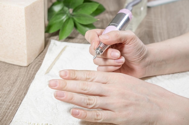 Kobieta manikiurzystka obrabia paznokcie i skórki lub usuwa lakier za pomocą maszyny do manicure użyj wiertarki elektrycznej pilnika do paznokci w salonie kosmetycznymManicure sprzętowy Proces lub operacja manicure z bliska