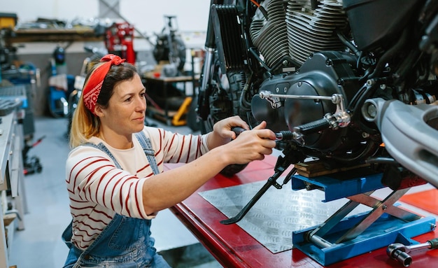 Kobieta mechanik przeglądająca motocykl nad platformą