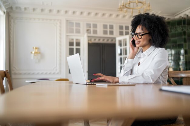 Kobieta menedżer w okularach używa laptopa, robi notatki na temat przestrzeni coworkingowej w biurze pracy