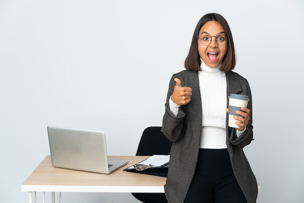 Kobieta młody biznes Łacińskiej pracująca w biurze na białym tle pokazano ok znak i kciuk w górę gestu