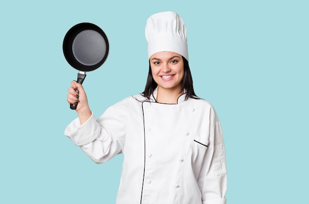 Kobieta młody kucharz trzymając patelnię na białym tle