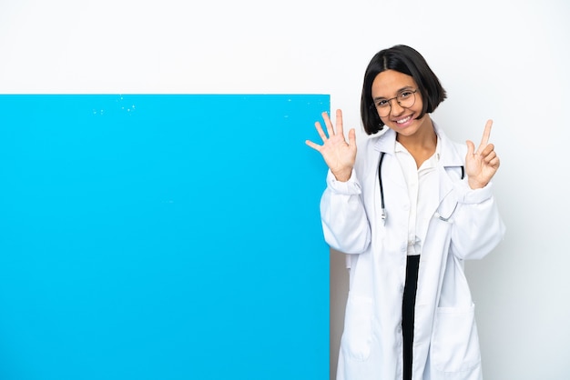 Kobieta młody lekarz rasy mieszanej z dużym plakietką na białym tle licząc siedem palcami