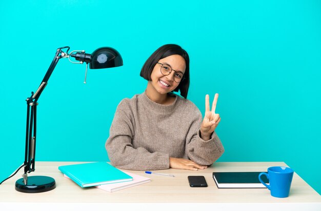 Kobieta Młody Student Rasy Mieszanej Studiuje Na Stole Uśmiechając Się I Pokazując Znak Zwycięstwa