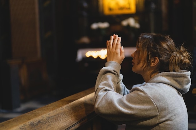 Zdjęcie kobieta modląca się na kolanach w starożytnej katolickiej świątyni boga ręce złożone w koncepcji modlitwy o wiarę, duchowość i religię koncepcja marzeń o nadziei na pokój