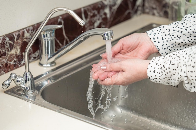 Kobieta myje ręce pod bieżącą wodą. Dezynfekcja rąk, higiena
