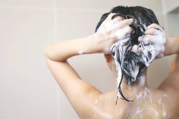 Zdjęcie kobieta myje włosy szamponem.