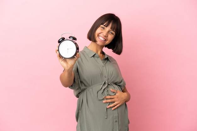 Kobieta Na Białym Tle W Ciąży I Trzymająca Zegar, Podczas Gdy Coś świętuje