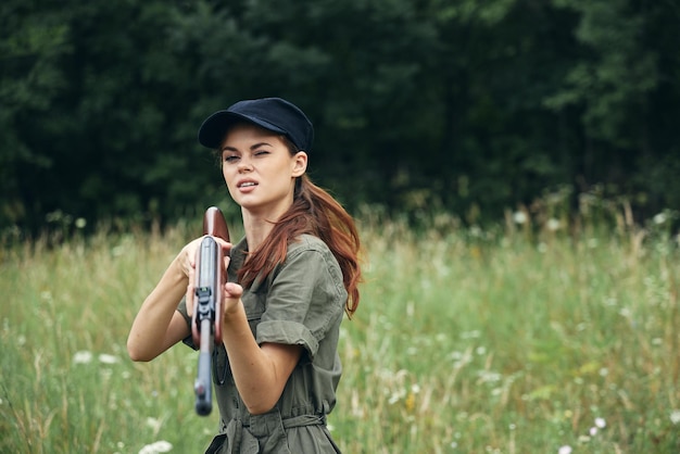 Kobieta na naturze kobieta trzymająca broń Patrzy w przyszłość na polowanie czarna czapka przycięty widok