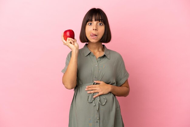 Kobieta na odosobnionym tle w ciąży i trzymająca jabłko