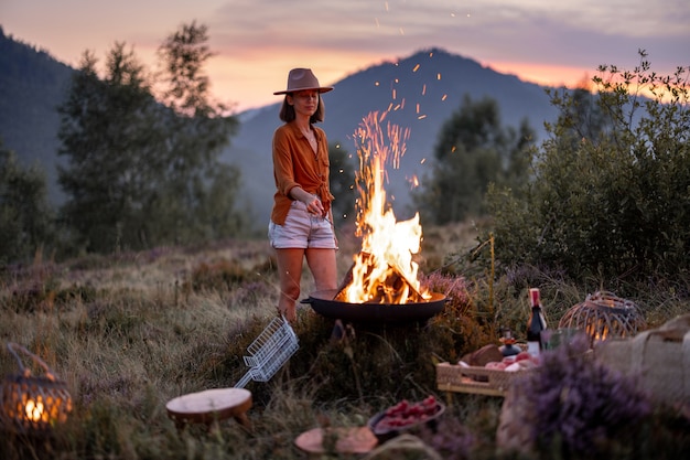 Kobieta na pikniku z ogniskiem w górach