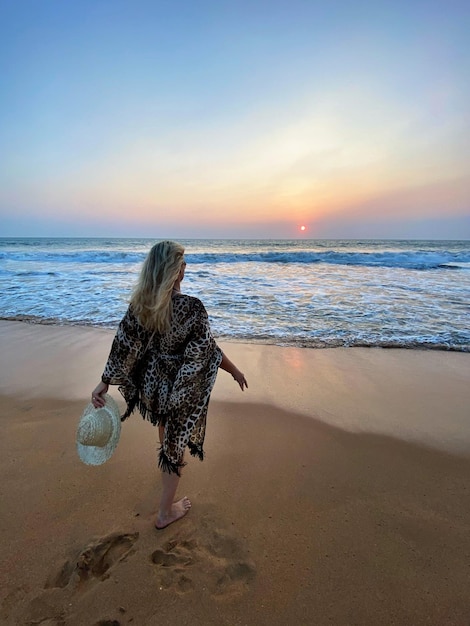 Zdjęcie kobieta na plaży na tle nieba podczas zachodu słońca