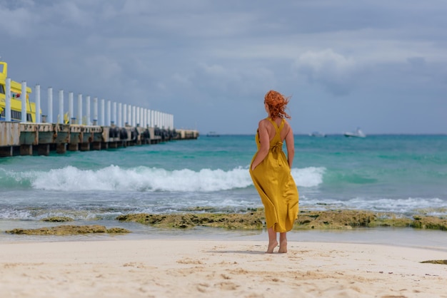 Kobieta na plaży patrzy na horyzont i idzie wzdłuż plaży w Meksyku