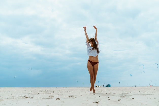 Kobieta na plaży rozciąga się stojąc tyłem do morza