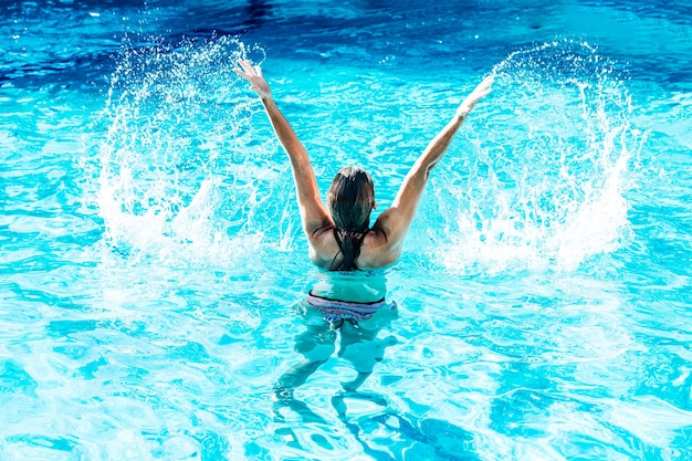 Kobieta na plecach w basenie podniosła z rękami wodę w rajskiej wodzie