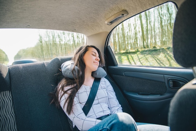 Kobieta na tylnych siedzeniach samochodu zapinana pasem koncepcja podróży samochodem sypialnym