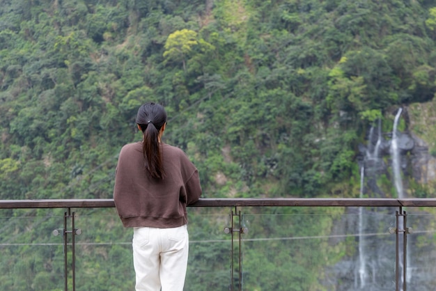 Kobieta na wędrówce patrzy na wodospad w Wulai na Tajwanie