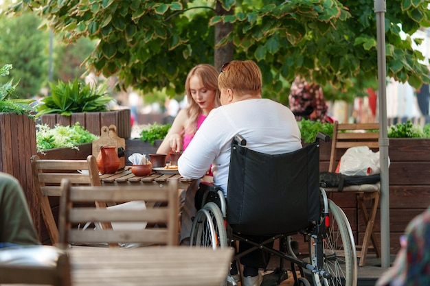 Kobieta na wózku inwalidzkim jedząca obiad w restauracji ze swoją młodą córką