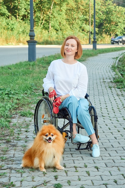 Zdjęcie kobieta na wózku inwalidzkim spaceruje z psem na świeżym powietrzu. międzynarodowy dzień osób niepełnosprawnych