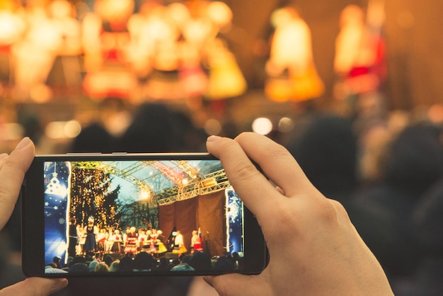 Kobieta nagrywa koncert na swoim telefonie, stojąc w tłumie