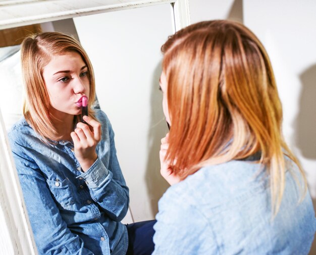 Kobieta nakładająca szminkę odbijająca się w lustrze w domu