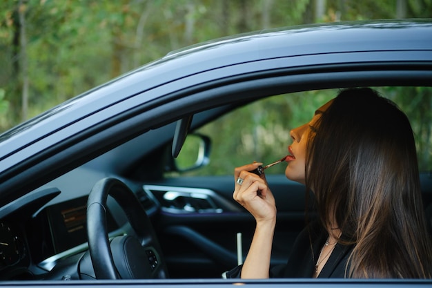 Kobieta nakładająca szminkę siedząc w samochodzie