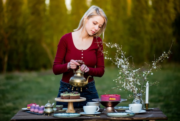 Kobieta nalewa herbatę podczas przyjęcia herbacianego w ogrodzie
