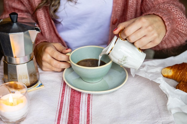 Kobieta nalewa mleko do kawy na śniadanie