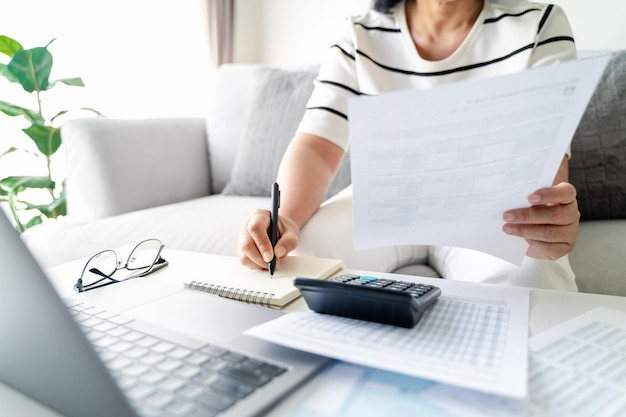 Zdjęcie kobieta nalicza podatek roczny za pomocą kalkulatora i wypełniając formularz indywidualnego zeznania podatkowego