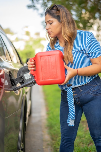 Kobieta napełniająca samochód galonem benzyny zaparkowanej w parku