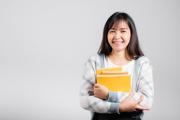 Kobieta nastolatka uśmiechnięta trzymając i przytulając ulubioną książkę dla kochanka, portret pięknej azjatyckiej młodej osoby nauczycielki studio strzał na białym tle na białym tle, koncepcja edukacji
