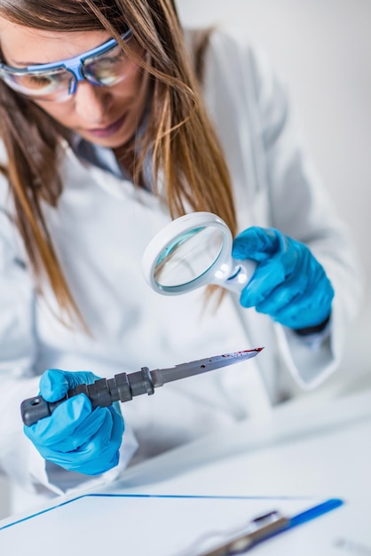 Zdjęcie kobieta naukowiec badająca nóż w laboratorium