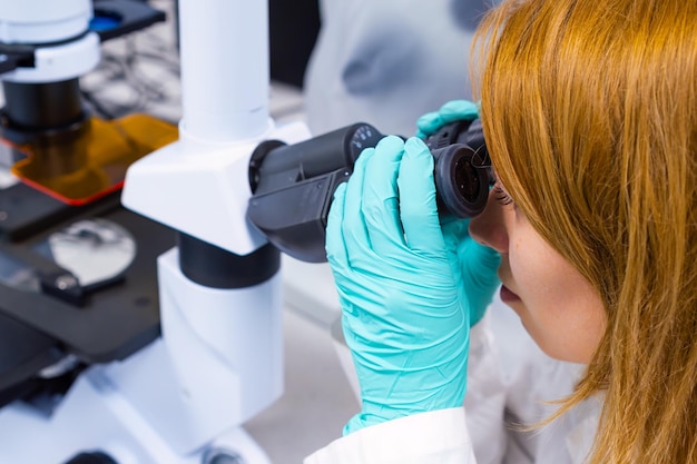 Kobieta naukowiec przeprowadza analizę w laboratorium, patrząc przez mikroskop