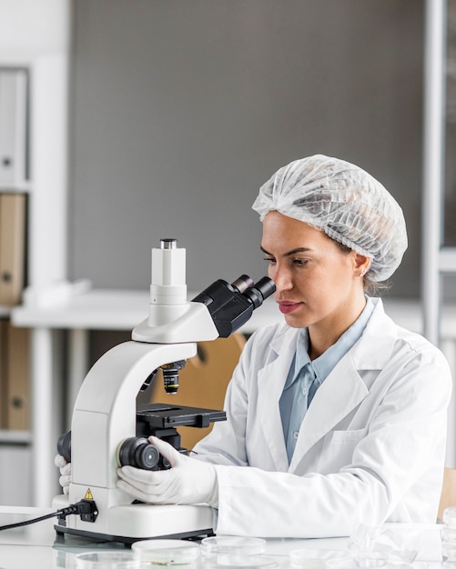 Zdjęcie kobieta naukowiec w laboratorium biotechnologii z mikroskopem i miejscem na kopię